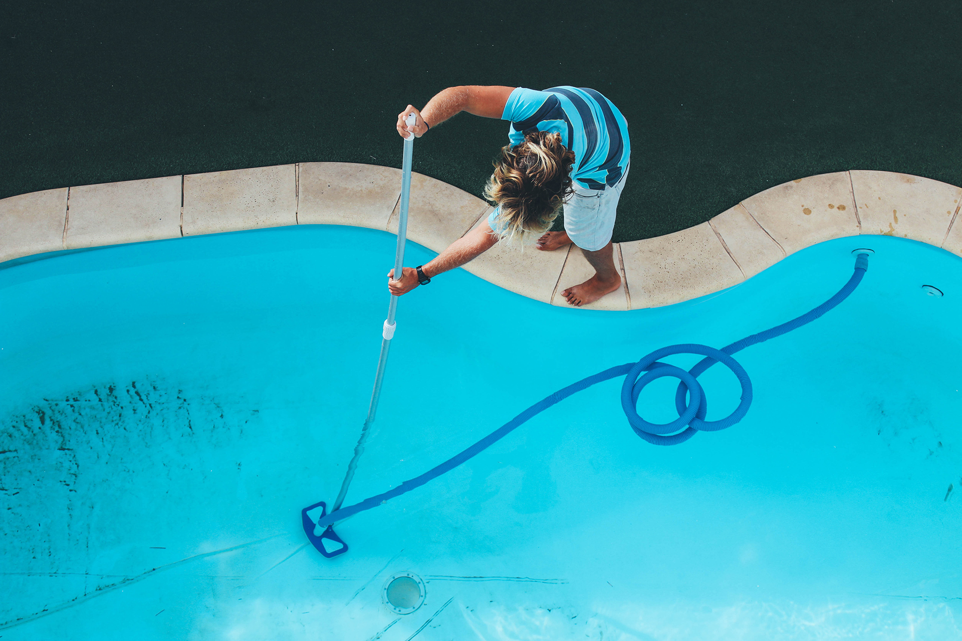 man cleaning pool with vacuum